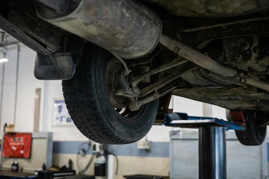 Steering & suspension repair — suspension components viewed from below on a lift